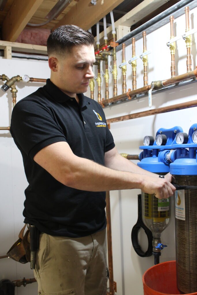 Technician installing a whole-home water filtration system in Lexington, MA